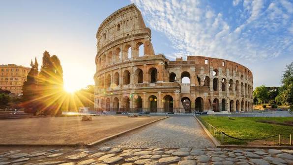 Where to Stay in Rome: The Ultimate 2026 Hotel Guide by Neighborhood & Budget The Colosseum in Rome at sunrise, with golden light breaking through its ancient arches and an empty cobblestone street in the foreground